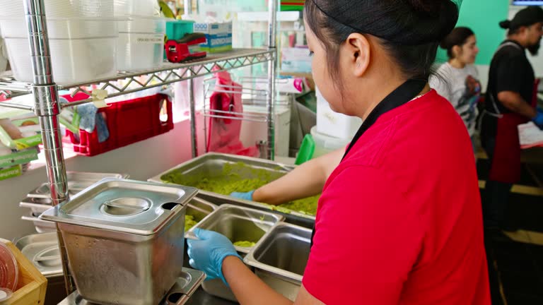 Young Restaurant Worker Putting Guacamole Into Small Containers