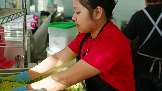 Young Restaurant Worker Mixing Up Guacamole in a Container