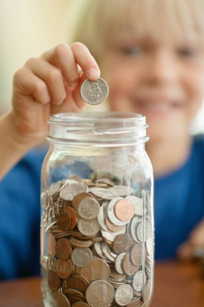 istock Little Boy Saving Coins In Money Jar 164461621