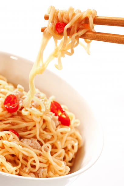 Instant noodles with pork on chopsticks.