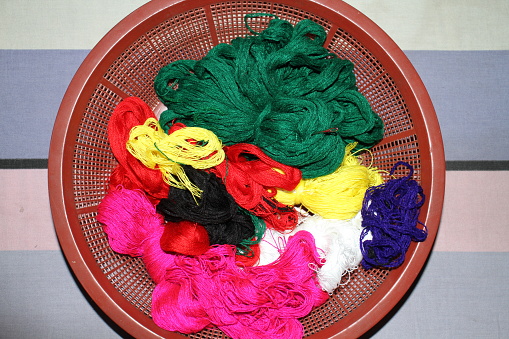 A woven basket containing balls of yarn in various colors, a tape measure and a knitted work in progress.
