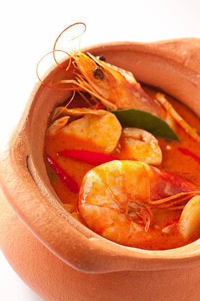 Spicy Thai Prawn soup (Tom Yam Kung). This famous Thai dish is very spicy and made with lemon grass, kaffir lime leaves, galangal and chili. Here it is photographed in a traditional terracotta soup bowl.