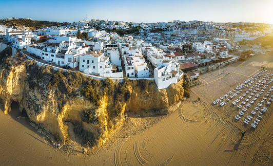 aerial view on Albufeira on the cliffs over the beach at sunrise hour, stitched panorama