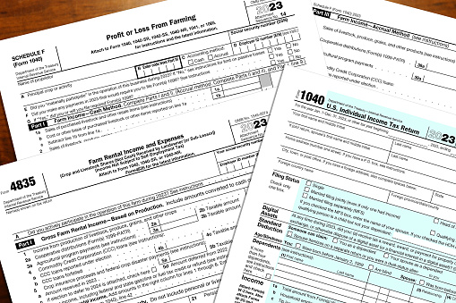 2023 IRS 1040 form and farming tax forms on a desk top.