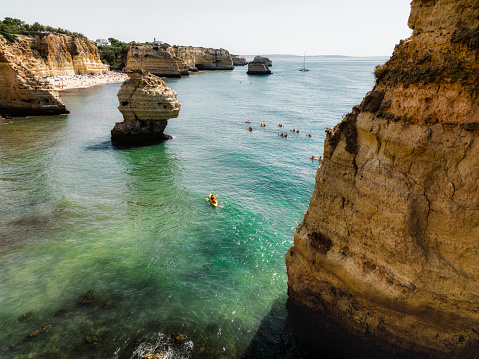 famous rock formation in Algarve, Portugal with a group of canoes on the water