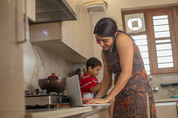 Son sitting on countertop while mother working in kitchen