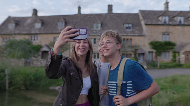 Three teenagers walking in beautiful village of Lower Slaughter on a warm summer evening