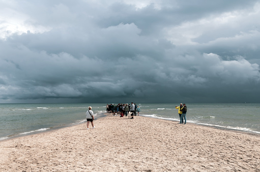 People walking along the seashore at cape Grene, Skagen Odde, Denmark - August 29, 2023.