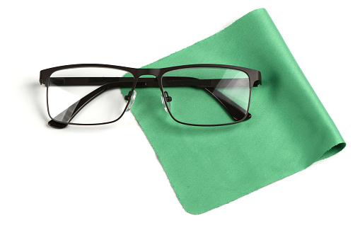 Glass cleaning green cloth napkin with a pair of glasses over it, composition isolated on white background. High resolution photo. Full depth of field.