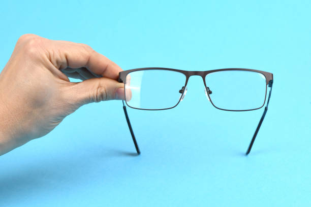 istock Hand holding plastic black glasses, isolated on blue background. 1644711252