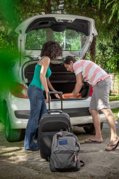 istock Young couple packing and loading their luggage in car trunk for vacation. 1644731156