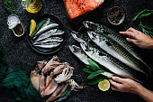 Point of view of chef hands arranging of fresh fish and seafood on black table