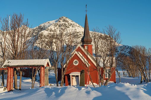 A red wooden Flakstad church in Lofoten archipelago , Nordland, winter in Norway on sunny day.