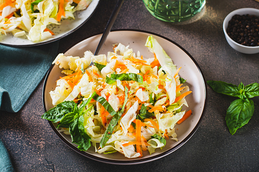 Salad cole slaw with fresh cabbage, carrots and basil on a plate
