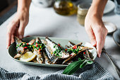 Woman's hand serving fried fish with lemon on dining table