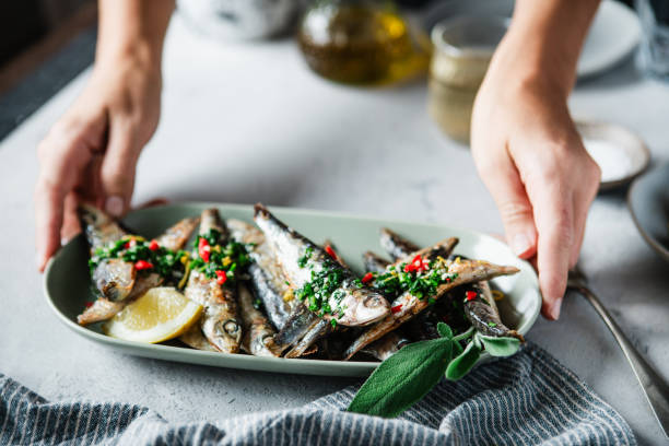 mão da mulher servindo peixe frito com limão na mesa de jantar - freshness fish food seafood - fotografias e filmes do acervo