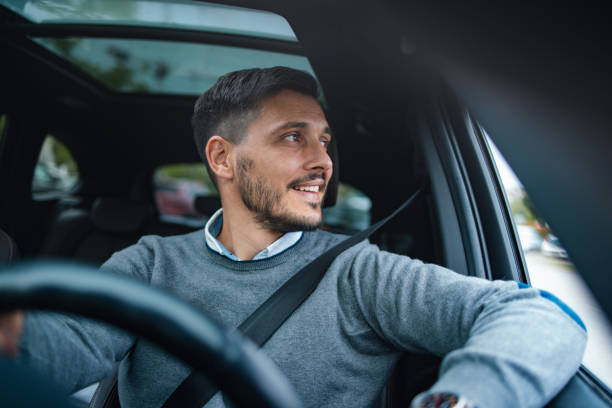 un bell'uomo d'affari felice che distoglie lo sguardo mentre guida la sua auto - car driving men business foto e immagini stock
