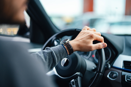 A close up view of an unrecognizable Caucasian male working as a taxi driver.