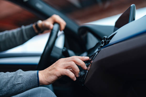 A Side View Of An Unrecognizable Businessman Turning His Radio On While Driving A close up view of an unrecognizable Caucasian male listening to music while sitting in the car. (cropped) car interior stock pictures, royalty-free photos & images