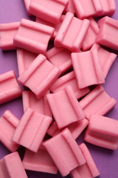 istock Tasty pink chewing gums on purple background, top view 1644779463