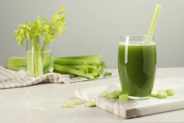 istock Glass of celery juice and fresh vegetables on light gray table, space for text 1644780530