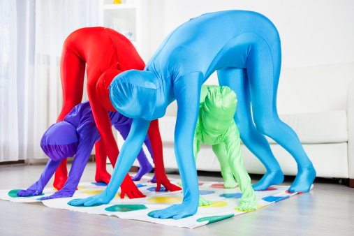 Family with two children playing floor game at home. Family wearing colorful zentai suits (zentai and stop racism concept).