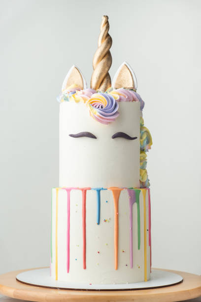 istock Big bunk cake with white chocolate frosting decorated with colorful drips, mastic eyebrows and golden ears with horn on top. Birthday party unicorn cake for a little girl on the white background. 1644788766