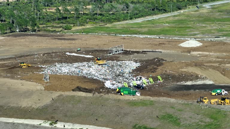 Solid waste disposal facility. Landfill dump site for garbage managment. Bulldozer tractors burying large amount of trash under the ground. Harmful impact of modern consumerism on environment