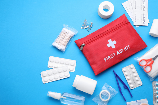 Flat lay composition with first aid kit on light blue background. Space for text
