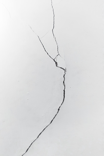 Crack on white wall close-up. The concept of brokenness, broken life, broken family. A symbol of mental health problems