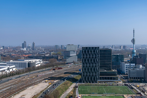 Amsterdam, The Netherlands-April 2022; High angle view of highway and train tracks and public transit exchange on Zuidas financial district and RAI Amsterdam Convention Centre and Amstel Tower visible