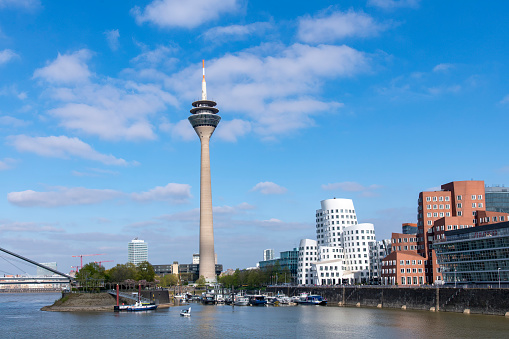 Dusseldorf, Germany-April 2022; Panoramic view over Medienhafen towards Rhine Tower and the Neuer Zollhof or Gehry Bauten (buildings) with bricks combined with stainless steel and bright white plaster