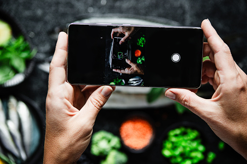 Hands of a woman looking at her video of her filming omega-3 rich food ingredients on her mobile phone. Point of view of a female looking at her phone videos.