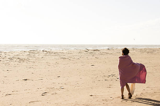 Woman watching sea from the beach stock photo