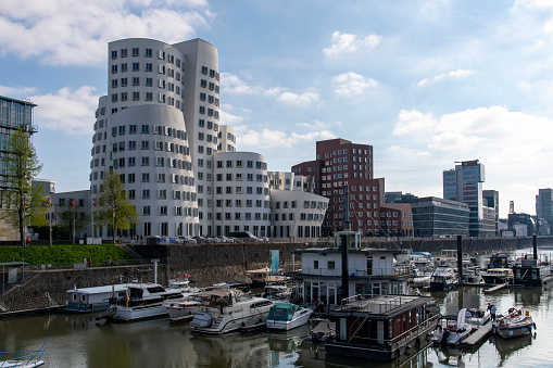 Dusseldorf, Germany-April 2022; View over the Medienhafen (media harbor) towards the Neuer Zollhof or Gehry Bauten (buildings) with bricks combined with stainless steel and bright white plaster