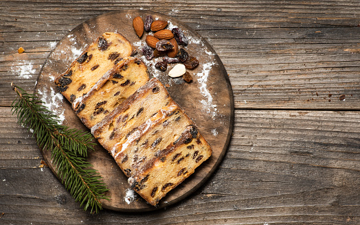 Christmas Stolen. Traditional sweet fruit loaf with powdered sugar on wooden table