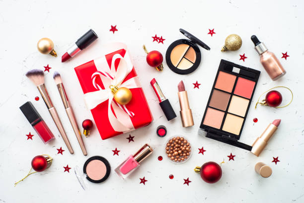 Winter cosmetic with holiday decorations on blue. Make up and cosmetic products and christmas decor on white. Christmas sale and gift concept. Flat lay image with copy space. makeup product photography stock pictures, royalty-free photos & images