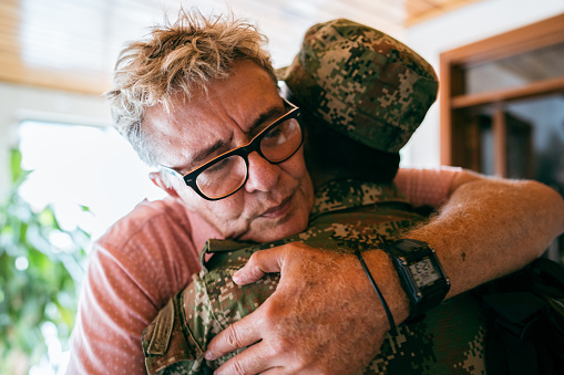 Senior man embracing his soldier son that returned home