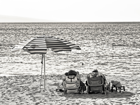 The Pacific Island of Maui in Hawaii on January 14, 2023:  Couple in beach chairs relaxing on the Kaanapali Beach with the comfort of a shade umbrella, Maui
