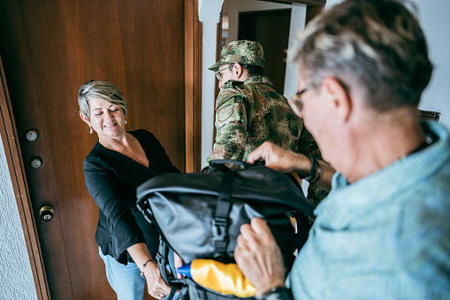 Parents helping soldier son with his bags after returning home