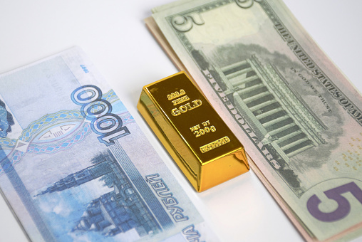 banknotes of dollars and Russian rubles, laid out in small bundles on top of a gold ingot. the concept of abandoning dollars and strengthening the economy during the sanctions pressure