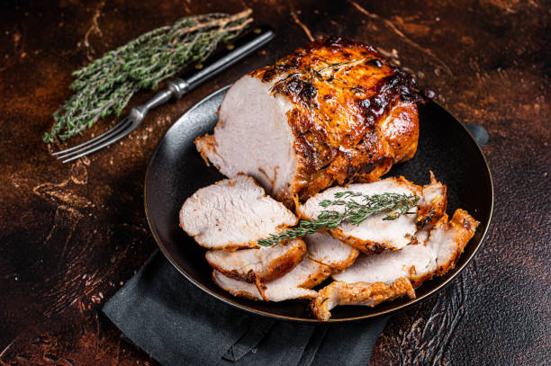 istock Roast rolled pork ham meat on plate with thyme. Dark background. Top view 1644900450