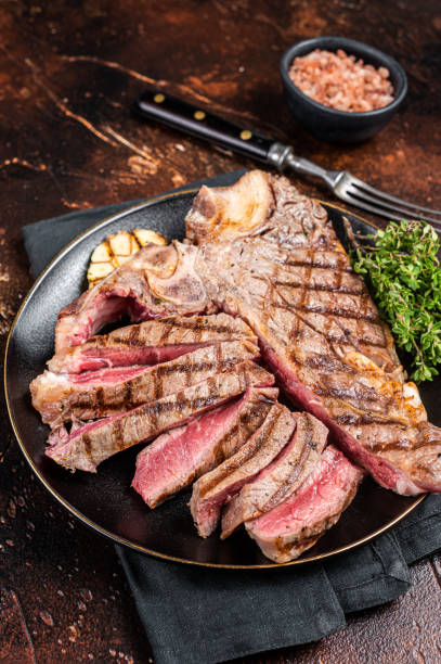istock Grilled Medium rare Porterhouse, T-Bone Steak sliced in a plate. Dark background. Top view 1644901528