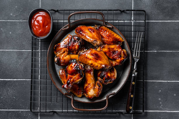 istock BBQ chicken wings in dip Barbecue sauce. Black background. Top view 1644903171