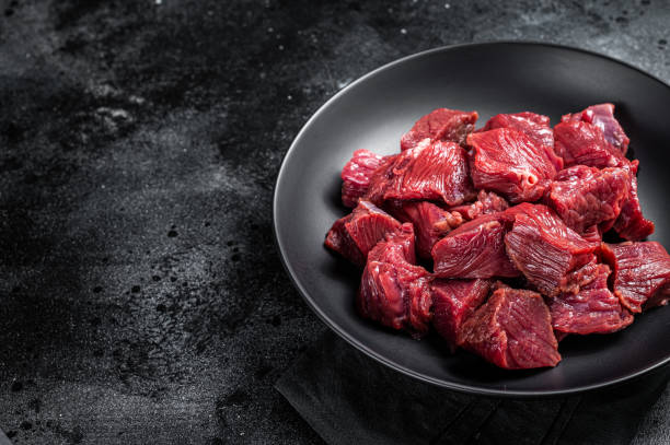 istock Raw Diced game meat of wild venison dear. Black background. Top view. Copy space 1644905466