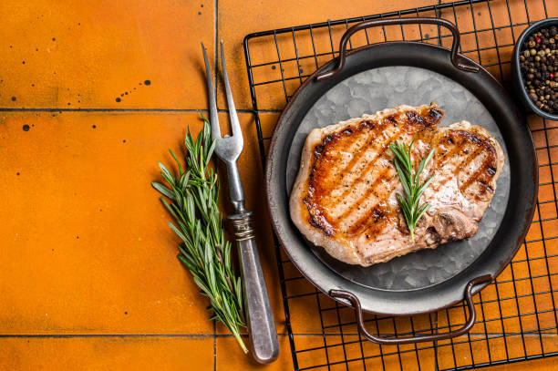 istock Grilled pork T bone chop meat steak. Orange background. Top view. Copy space 1644906598