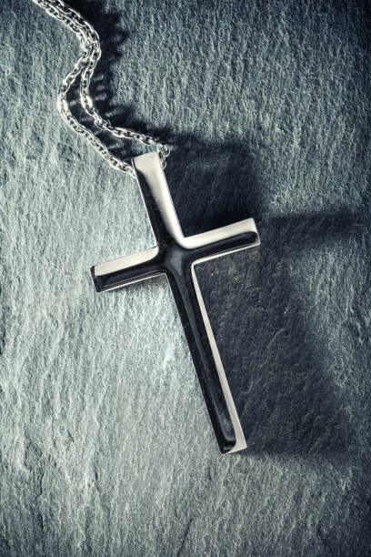 istock Christian cross necklace on slate background with the crucifix casting a dark shadow. 1644911542