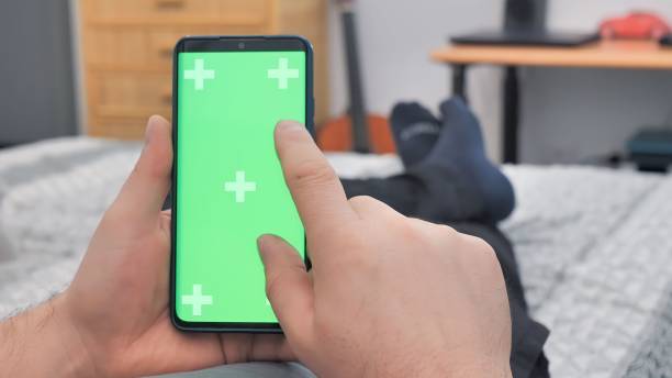 istock Man lying on couch using smartphone with chroma key green screen at night 1644947221