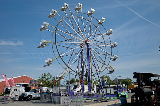 Elizabethtown, PA, USA-August 22, 2023: A Ferris wheel at small town carnival and country fair. It is an amusement ride consisting of a rotating upright wheel with multiple passenger carrying carts.