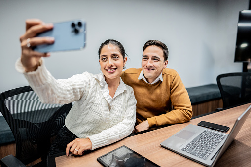 Coworkers taking a selfie using mobile phone at office